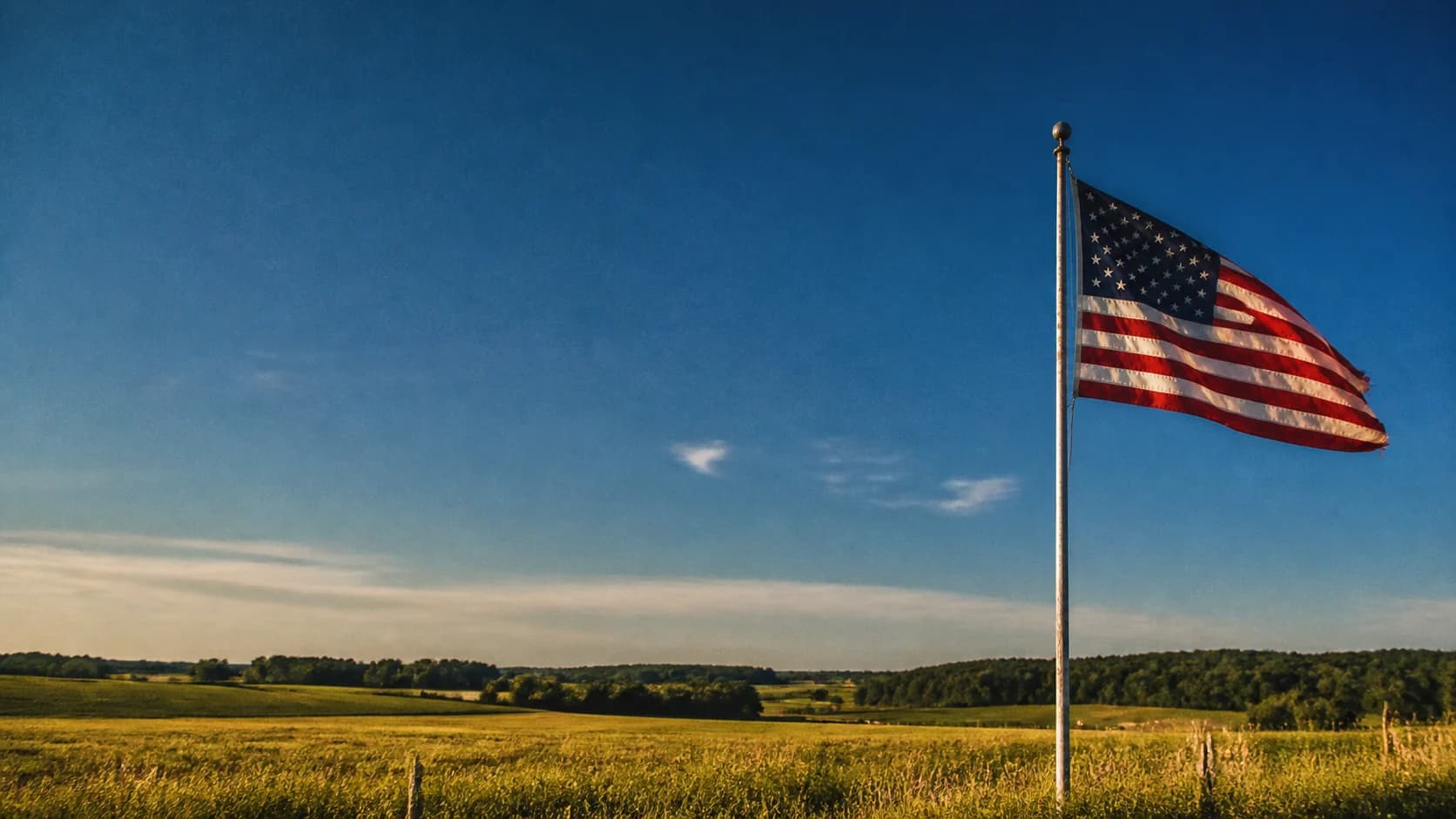 An American flag above open farmland at golden hour